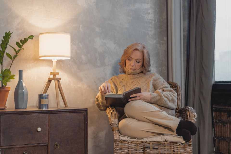 woman reading in modern gray living room next to table lamp